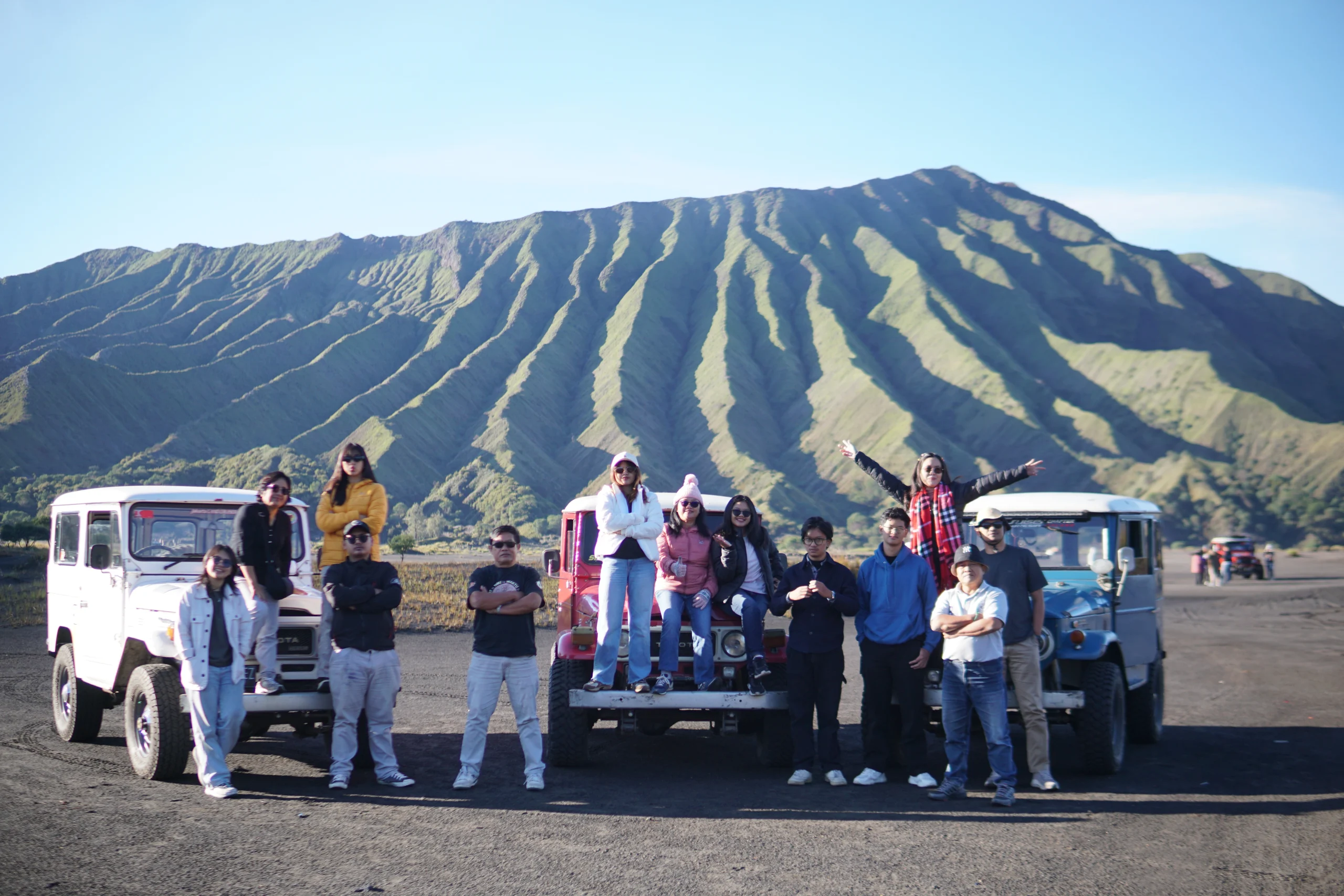 Rombongan wisatawan berfoto bersama jeep di lautan pasir Bromo depan perbukitan