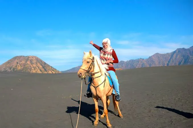 Wisatawan menunggang kuda di lautan pasir berbisik Bromo menuju Pura Luhur Poten.