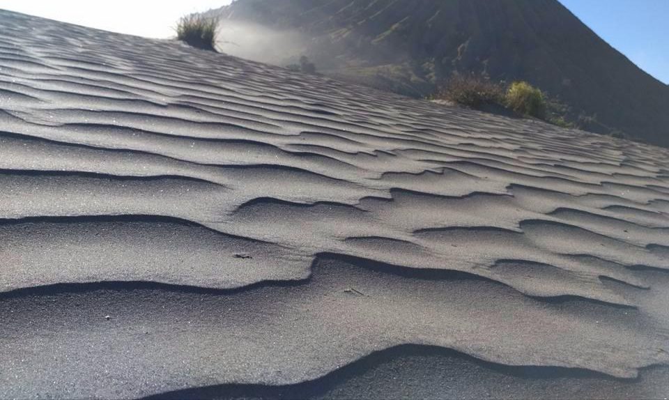 Butiran pasir halus di pasir berbisik Bromo yang ditiup angin, menunjukkan fenomena suara bisikan.