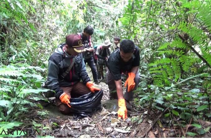 Pendaki sedang memungut sampah di jalur pendakian