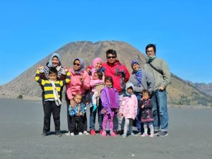Keluarga bahagia menikmati momen matahari terbit saat membawa anak-anak ke Bromo.