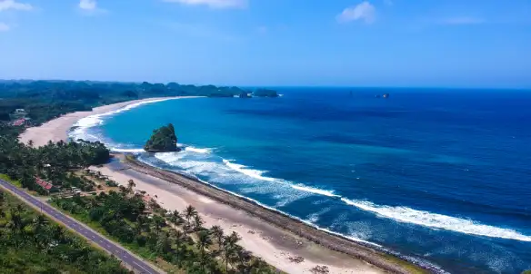 Pemandangan drone garis pantai selatan Malang dengan air biru jernih